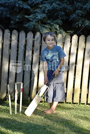 Boy playing cricket in back garden