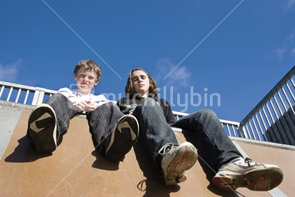 Boys resting on skateboard ramp