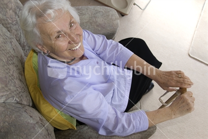 Elderly lady in her armchair holding a walking stick