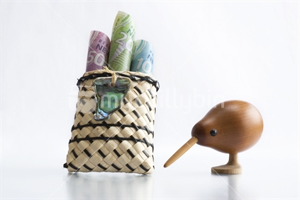 NZ currency in little flax bag with paua shell decoration and wooden kiwi bird