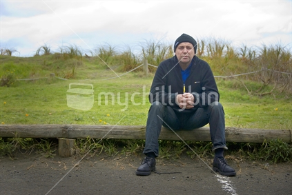 Man sitting on a small log rail