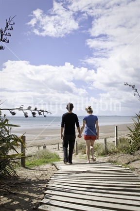 Young couple walking down beach access
