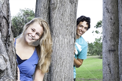 Young couple hiding behind trees