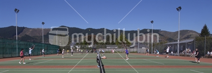 Adults playing tennis, with hills in the background.