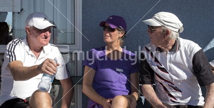 Mature tennis players, waiting in the sun for the next game