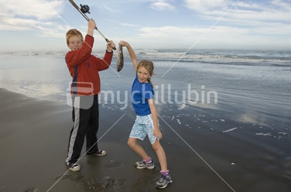Two kids fishing at mouth of Waimakariri River, Kairaki, New Zealand