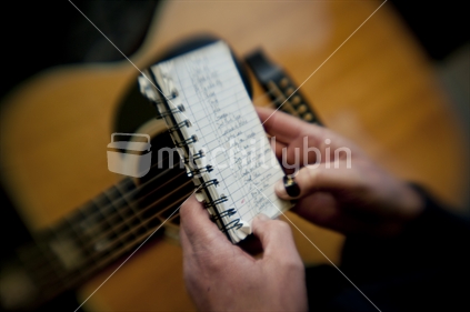 Hands of guitar player looking through list of songs