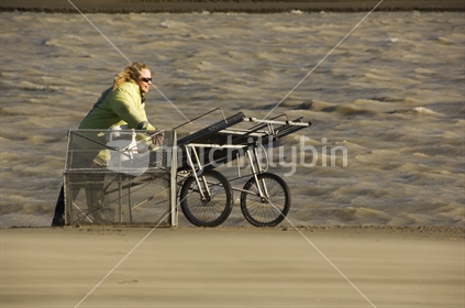 Woman whitebaiting at the mouth of the Waimakariri River with northwester blowing sand. New Zealand