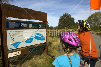 Children 12 and 8 years on bicycles looking at Northbrook Wetlands map Rangiora