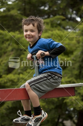 Little boy (5 years old) playing on playground see-saw  