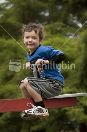 Little boy (5 years old) playing on playground see-saw  