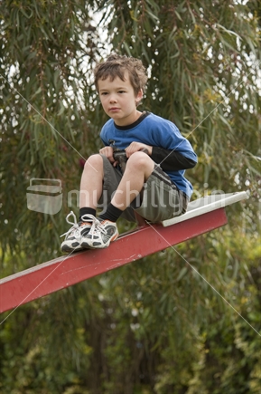 Little boy (5 years old) playing on playground see-saw 