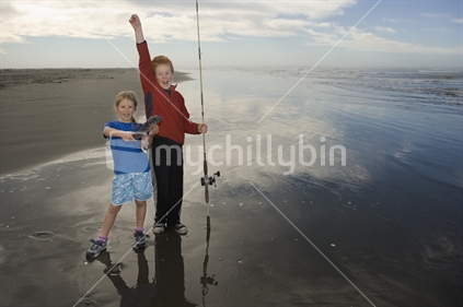 Children (girl 8 years boy 11 years) fishing at mouth of Waimakariri River Kairaki New Zealand