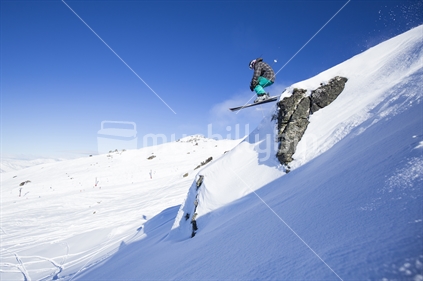 skier jumps cliff on beautiful sunny day, cardrona, wanaka