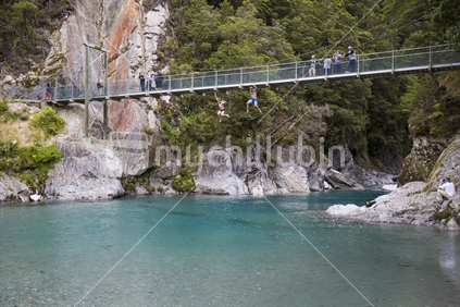 men jump from bridge in to blue pools