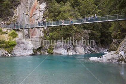 men jump from bridge in to blue pools