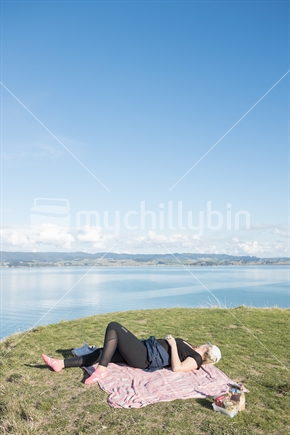 Young Woman Resting On Blanket, Looking Away, With Scenic Backdrop