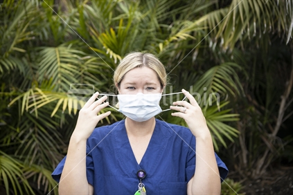 Female nurse putting on protective face mask