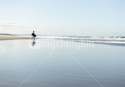 Reflection of male bodyboarder walking to a beautiful beach