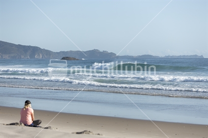 Woman relaxing on white sand beach (focus surf)