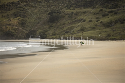 Surfer on expansive sandy beach