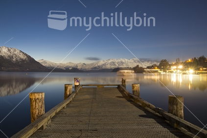 Slow shutter night photo over Lake Wanaka enhanced by boat movement and star trails. 