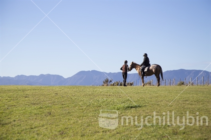 Young female riding horse with trainer by her side