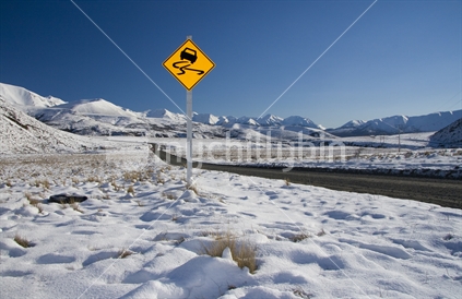 Windy road sign on gravel road