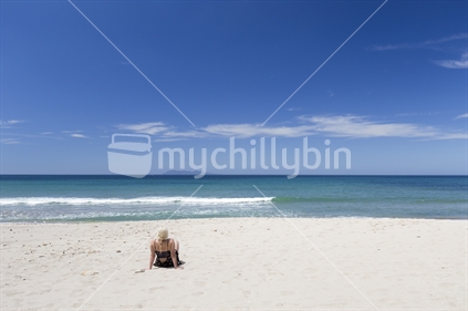 Female sunbathing at Orokawa beach, Waihi, Coromandel