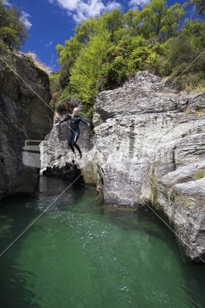 female leaps from cliff at motatapu gorge, southern lakes, south island