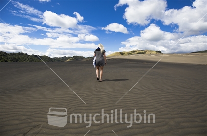 Black sand dunes and female walking in distance near Lake Waimanu, Bethells beach, Auckland