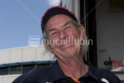 New Zealand male with huge smile, wearing cap. Head and shoulders.