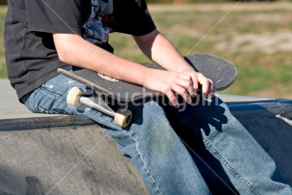 Boy sitting with skateboard on his lap