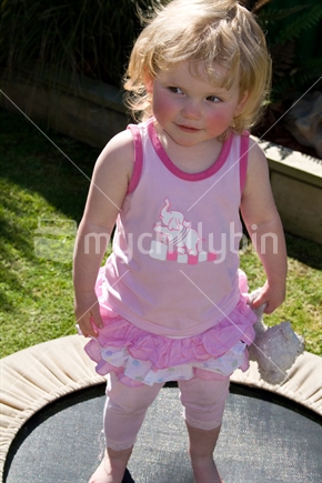 Blonde-haired little girl in pink on mini tramp