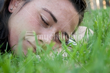 New Zealand woman resting on grass lawn.