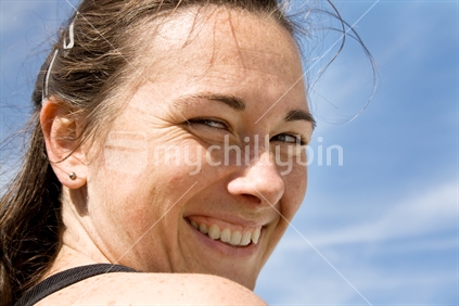 Happy New Zealand brunette woman, looking back over shoulder.