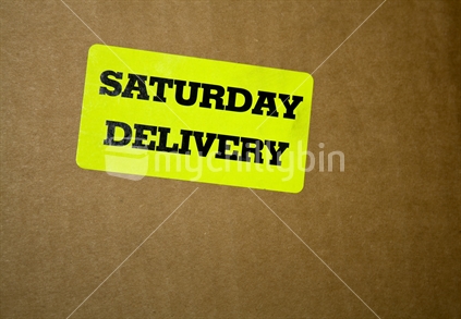 "Saturday Delivery" courier label on brown cardboard