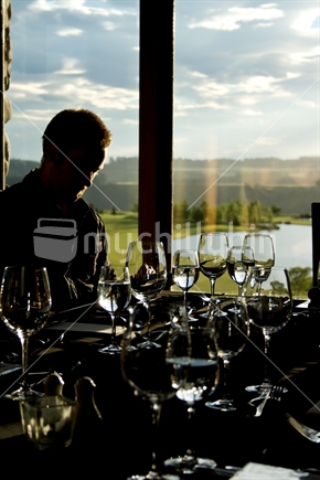 Silhouette, person at a restaurant with a rural New Zealand view in the early evening light.
