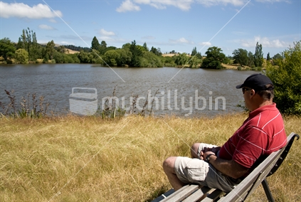 Man relaxing in the sun, by a lake.