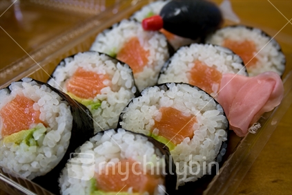 Takeaway tray of salmon and avocado sushi (with soy sauce and pickled ginger)