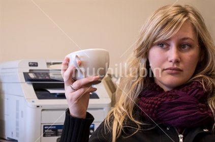 Blonde woman relaxing with a cup of coffee in an office