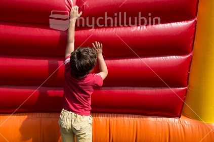 Boy climbing up the side of a bouncy castle