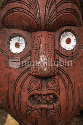 Maori wooden carving of a face with paua shell eyes