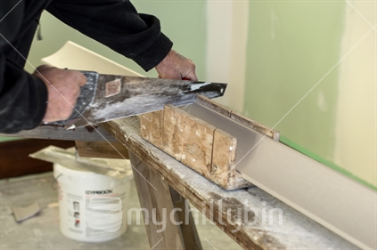 Plasterer cuts coving to length to install in a 1920's bungalow  undergoing renovations