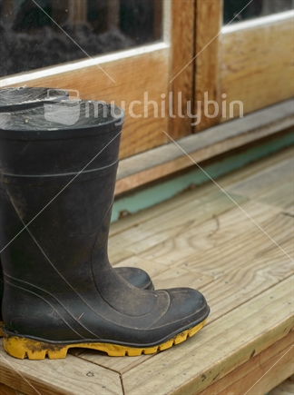 Gumboots left on a wooden doorstep by French doors