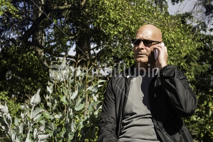 Man on mobile phone in a park, serious expression