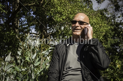 Man on mobile phone in a park, serious expression