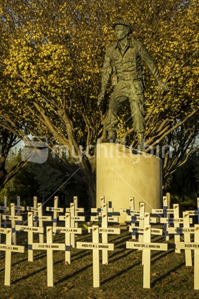 ANZAC Day commemorative crosses in front of statue of a soldier