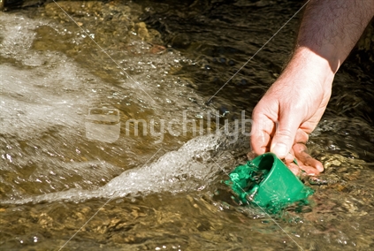 Filling a cup with water from a stream