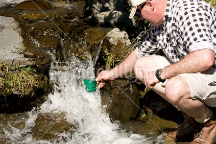 Man getting a drink from a stream